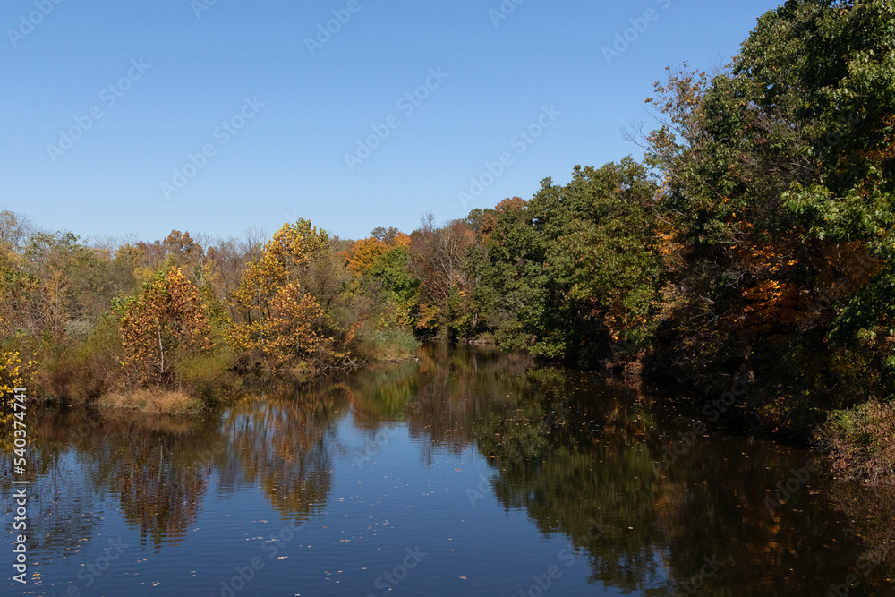 Beautiful Fall foliage around very reflective lake. This picture was taken in the Green Lane reservoir nature center close to Pennsburg in Pennsylvania. The leaves have really pretty Autumn colors.