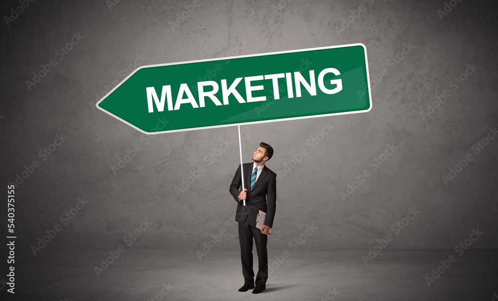 Young business person in casual holding road sign Young business person in casual holding road sign