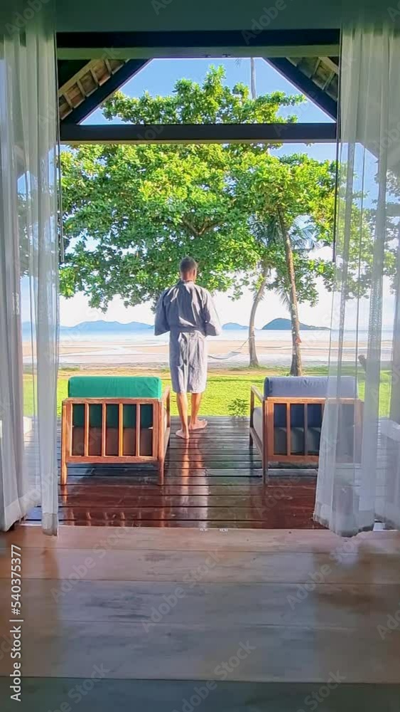 Young men wake up drinking coffee in a beach bungalow on a tropical