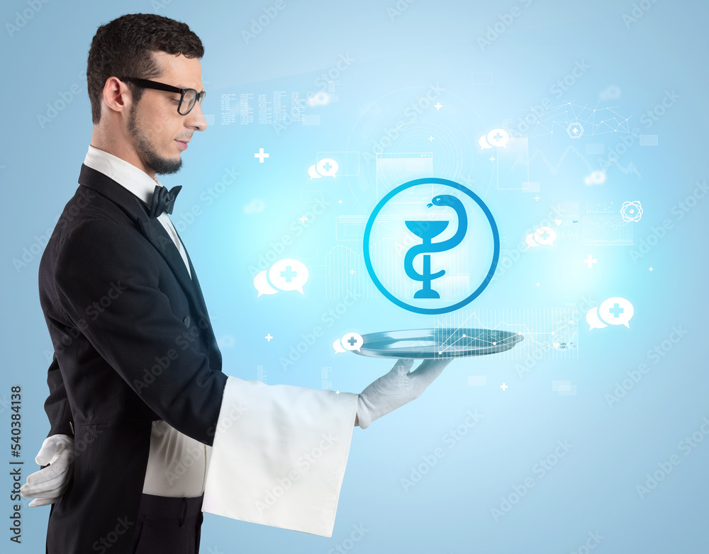 Handsome young waiter in tuxedo holding healthcare icons on tray Handsome young waiter in tuxedo holding healthcare icons on tray