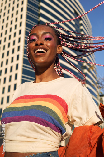Portrait of young non-conforming with braids smiling in the city