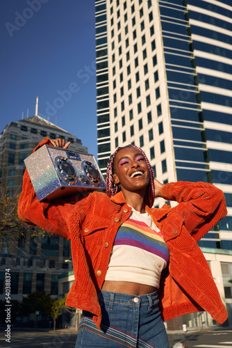 Portrait of young non-conforming with braids with boombox in city
