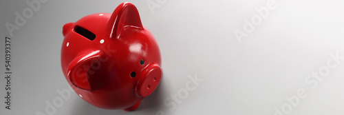 Red piggybank container on grey surface with hole for coins, empty ceramic pig for money