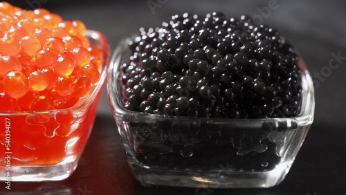 Red and black Caviar rotated over black background. Close-up salmon caviar rotation. Delicatessen.