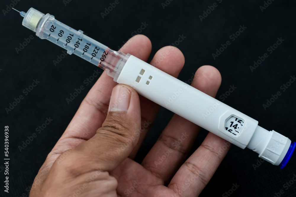 Naklejka premium Insulin pen isolated on black background. Medical devices are used for self-injection for the treatment of diabetes. World diabetes day and health care concept.