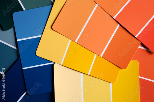 Generic color swatches scattered on a table. Swatches are in various autumnal shades of yellows and oranges, with complimentary blues as well. Fall color schemes. Interior design color pallet.
