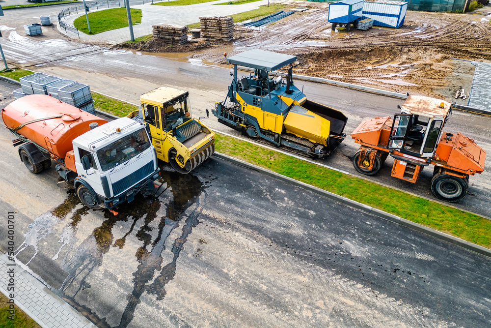 Asphalt laying equipment. Asphalt paver machine on the road repair site. Road renewal process, construction work. View from above. Drone photography.