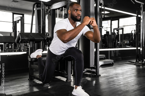 Strong african sportsman doing bulgarian lunges in a gym.