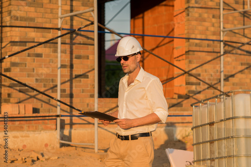 civil engineer or architect in hardhat at construction site checking schedule or work plan