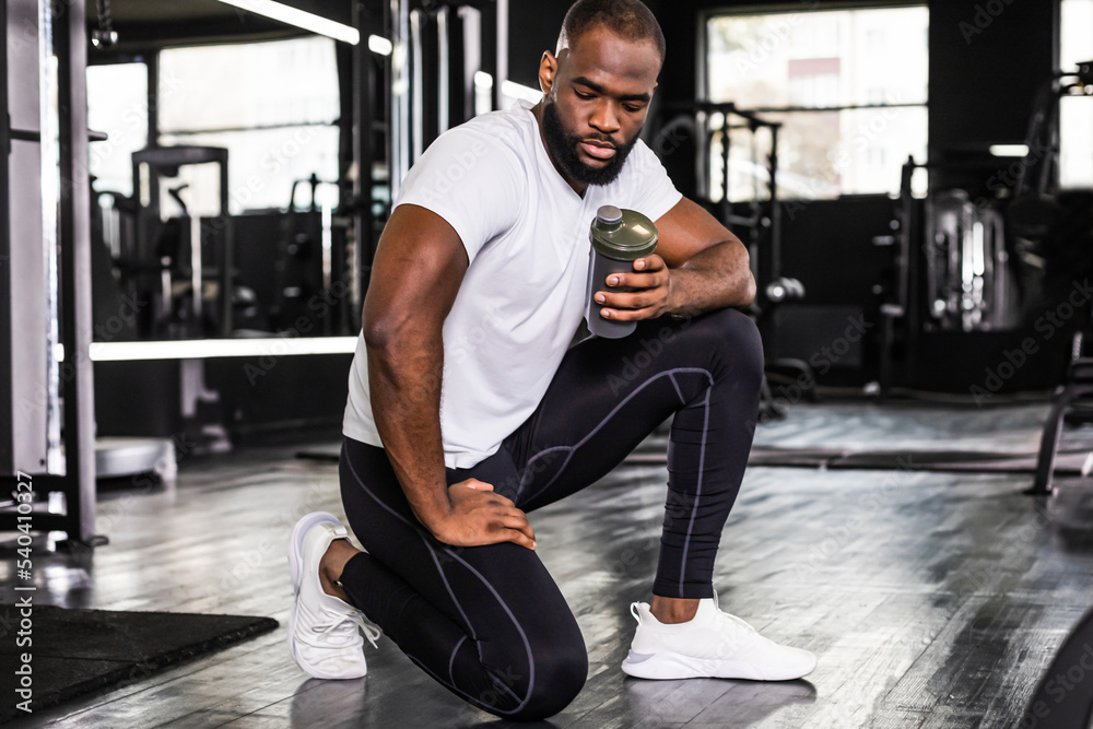 Obraz premium Sporty african man resting, having break drinking water after doing exercise.