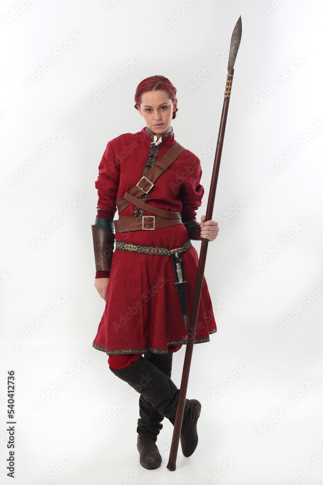full length portrait of beautiful woman wearing a red medieval fantasy warrior costume with leather armour, holding weapons. Standing pose isolated on white studio background. full length portrait of beautiful woman wearing a red medieval fantasy warrior costume with leather armour, holding weapons. Standing pose isolated on white studio background.