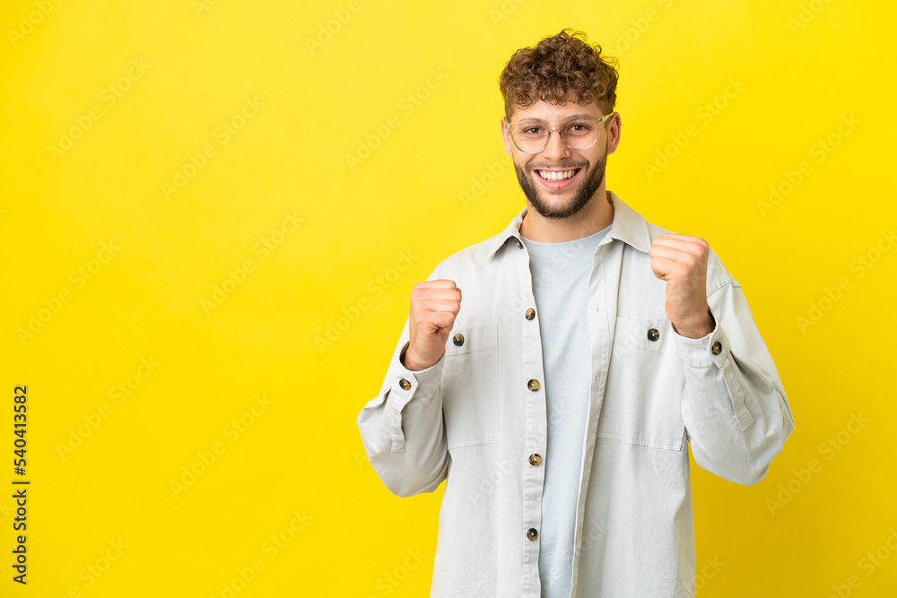 Young handsome caucasian man isolated on yellow background celebrating a victory in winner position Young handsome caucasian man isolated on yellow background celebrating a victory in winner position