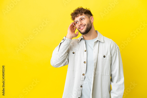 Young handsome caucasian man isolated on yellow background thinking an idea