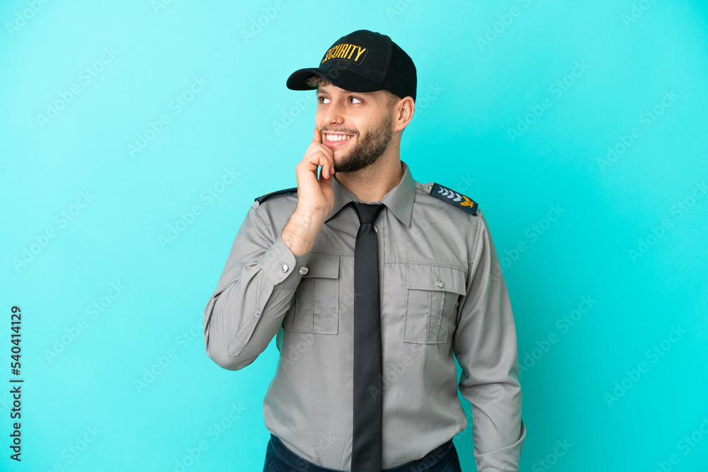 Young security man isolated on blue background thinking an idea while looking up Young security man isolated on blue background thinking an idea while looking up