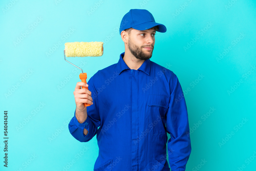 Painter caucasian man isolated on blue background looking to the side Painter caucasian man isolated on blue background looking to the side