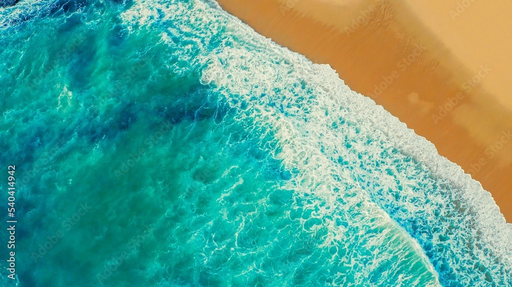  Drone view of blue waves and sandy beach.  Beautiful ocean beach with yellow sand, aerial view. Top view - Beautiful Ericeira beach is famous tourist destination.  Atlantic Ocean, Portugal.