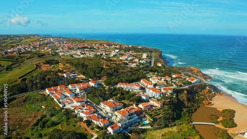 Aerial view of a small European town against blue sky and Atlantic Ocean. Drone view of a beautiful European city with a hilly landscape on ocean background. Beautiful natural landscape. Portugal. © Valua Vitaly