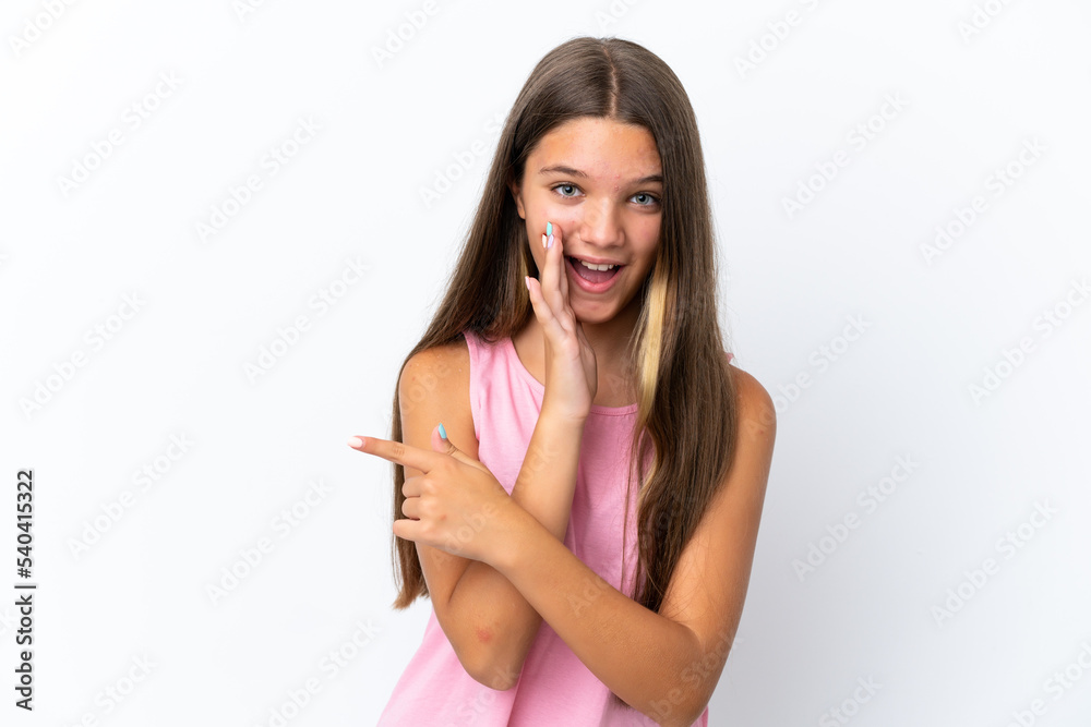 Little caucasian girl isolated on white background pointing to the side to present a product and whispering something Little caucasian girl isolated on white background pointing to the side to present a product and whispering something