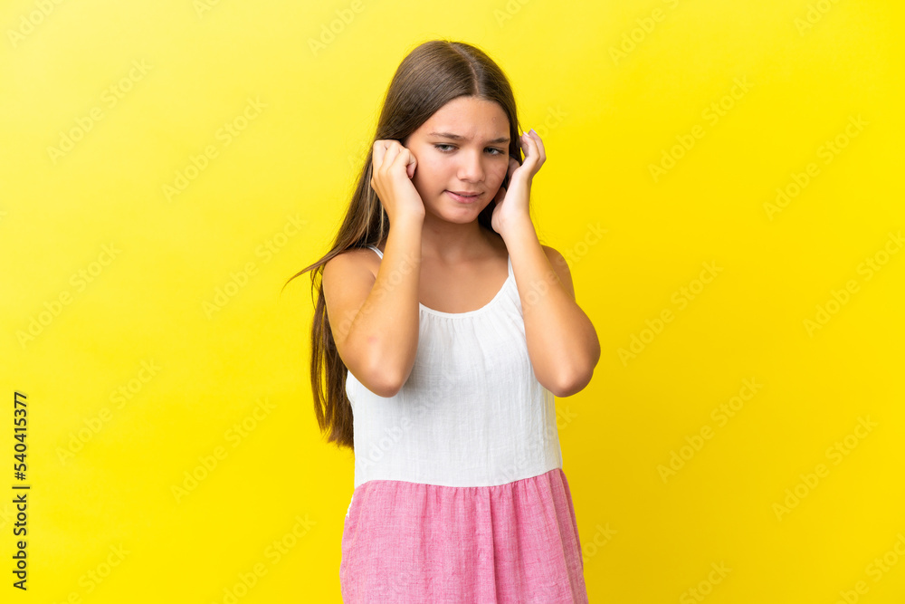 Little caucasian girl isolated on yellow background frustrated and covering ears
