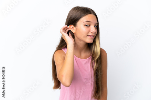 Little caucasian girl isolated on white background listening to something by putting hand on the ear