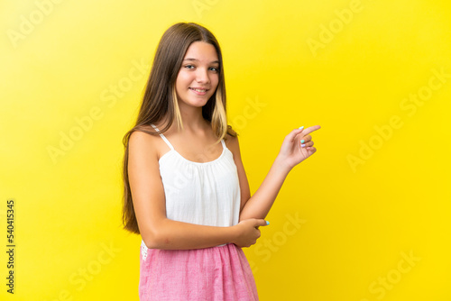 Little caucasian girl isolated on yellow background pointing finger to the side