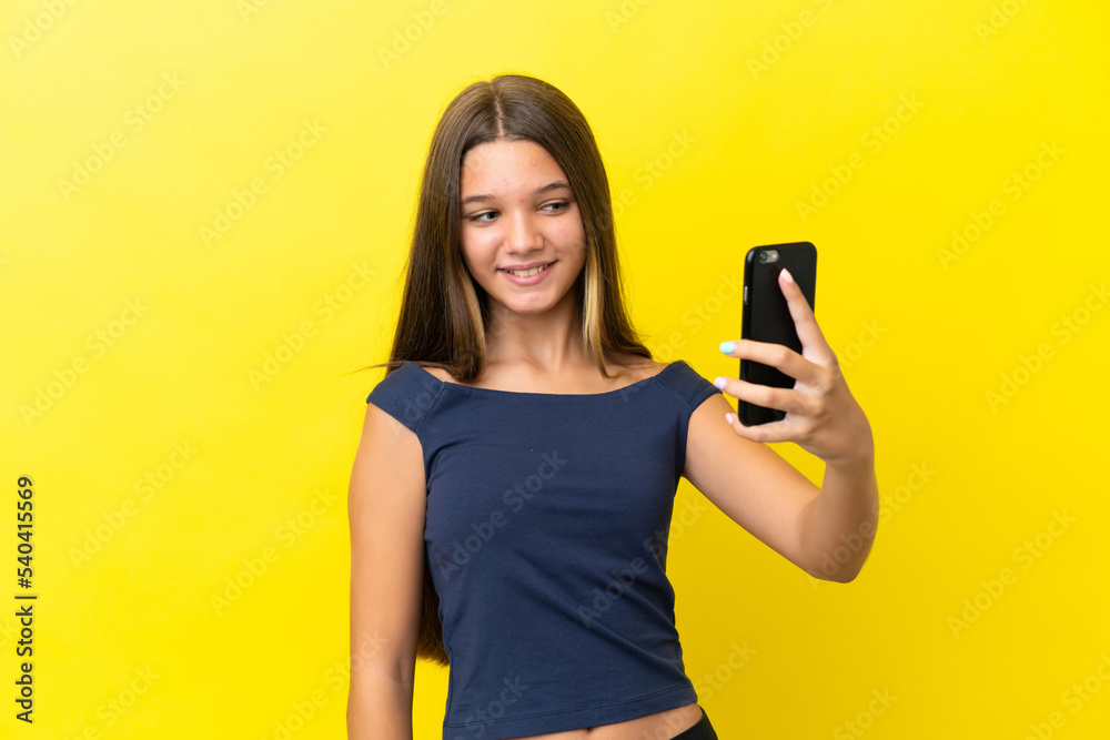 Little caucasian girl isolated on yellow background making a selfie Little caucasian girl isolated on yellow background making a selfie