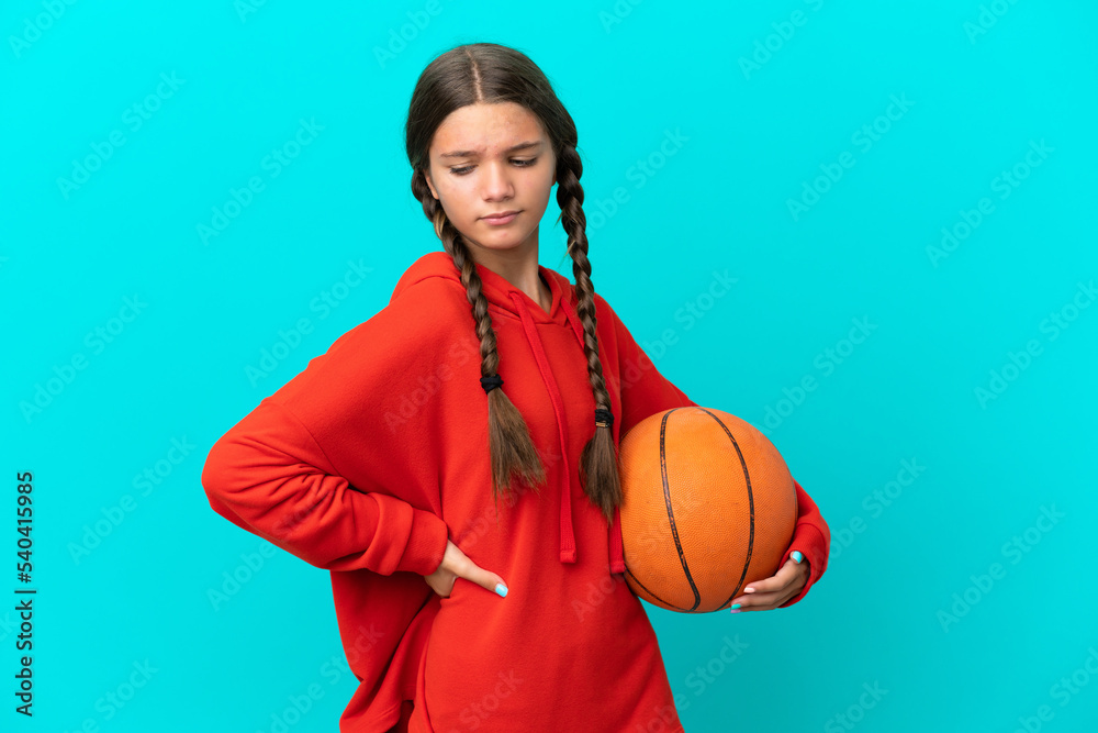 Little caucasian girl playing basketball isolated on blue background suffering from backache for having made an effort