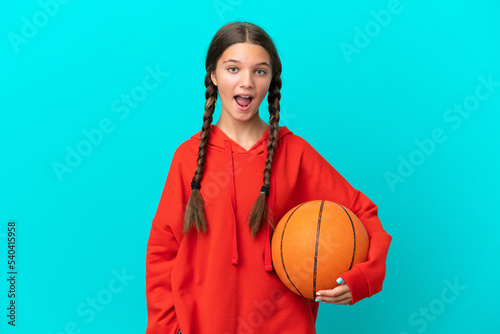 Little caucasian girl playing basketball isolated on blue background with surprise facial expression © luismolinero