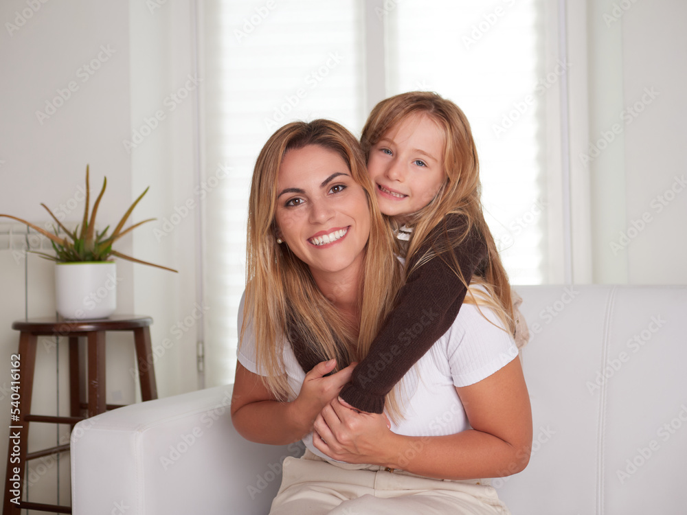 Young beautiful mother playing with daughter in livingroom