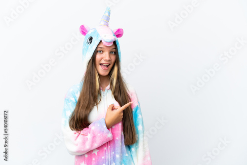 Little caucasian girl wearing unicorn pajama isolated on white background surprised and pointing side
