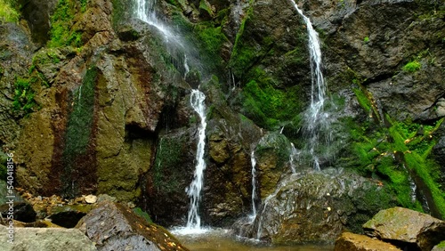 A calm, small waterfall, divided and split to few streams, delicately flowing between the rocks in an autumn environment. a 4K video clip, Bulgaria. photo