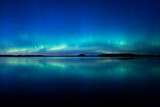 Northern lights dancing over calm lake in Farnebofjarden national park in north of Sweden