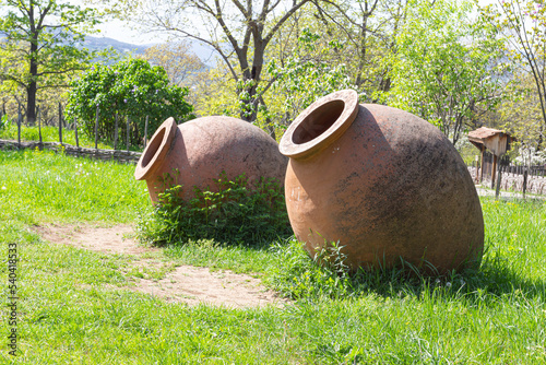 A large clay jar for wine called a "querti" lies on the grass