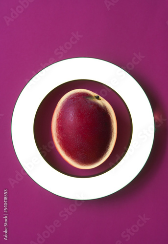 Original creative photo of ripe fresh pink mango on pink background in round frame with light
