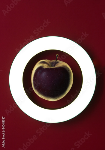 delicious healthy fresh red apple in good light in round frame on red background, top view