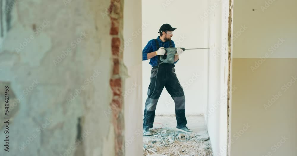Portrait of a young man with an electric drill and making a hole in the wall. Interior design and home renovation concept. Portrait of a young man with an electric drill and making a hole in the wall. Interior design and home renovation concept.