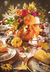 Thanksgiving celebration traditional dinner table setting concept. Festive decorated Thanksgiving table with centerpiece from big pumpkin and bouquet of flowers and candles