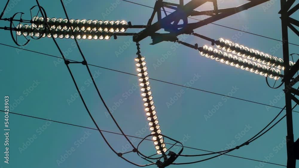 Power lines with sun rays on blue sky. High voltage substation ...