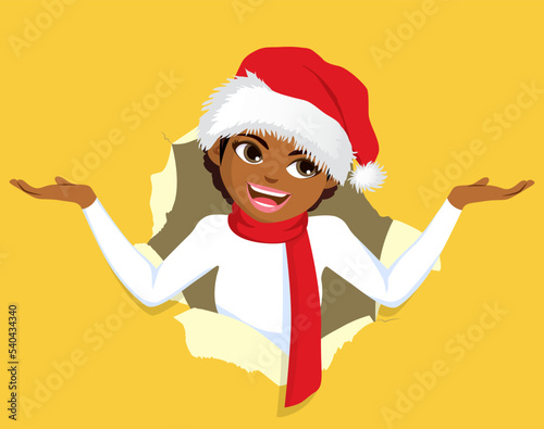 Positive glad woman wearing Christmas hat with exciting and amazed face expression on yellow copy space with open hand. Female person in a paper hole popping out