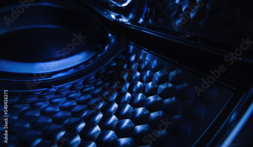 Interior view of the washing machine drum in dark cool colors. Perspective view of the inside of the blue washing machine drum. Close-up, partial focus.