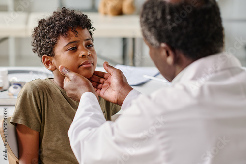 African little boy visiting pediatrician at hospital, he complaining on his sore throat photo