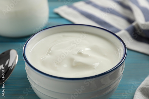 Bowl of tasty yogurt on light blue wooden table, closeup
