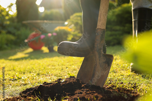 Man digging soil with shovel outdoors on sunny day, closeup. Gardening time photo