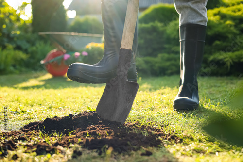 Man digging soil with shovel outdoors on sunny day, closeup. Gardening time