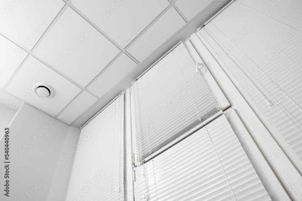 Fototapeta premium Window with closed white horizontal blinds indoors, low angle view