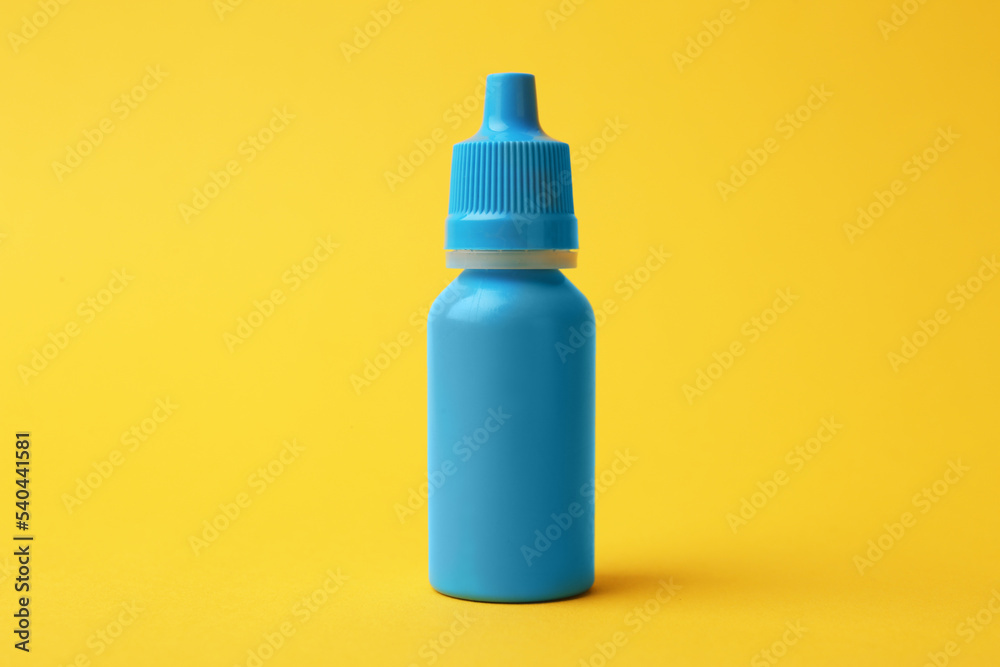 Bottle of medical drops on yellow background Bottle of medical drops on yellow background