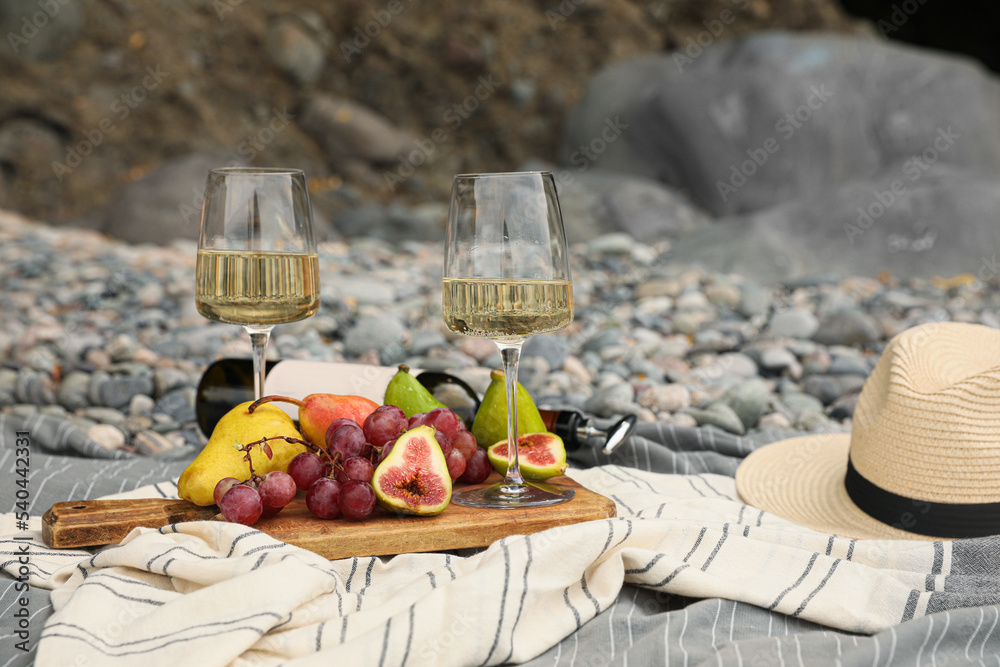White wine and fresh fruits on picnic blanket outdoors