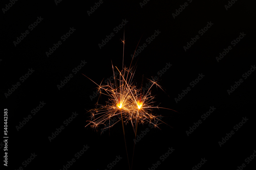 Two burning sparkler sticks glowing in dark