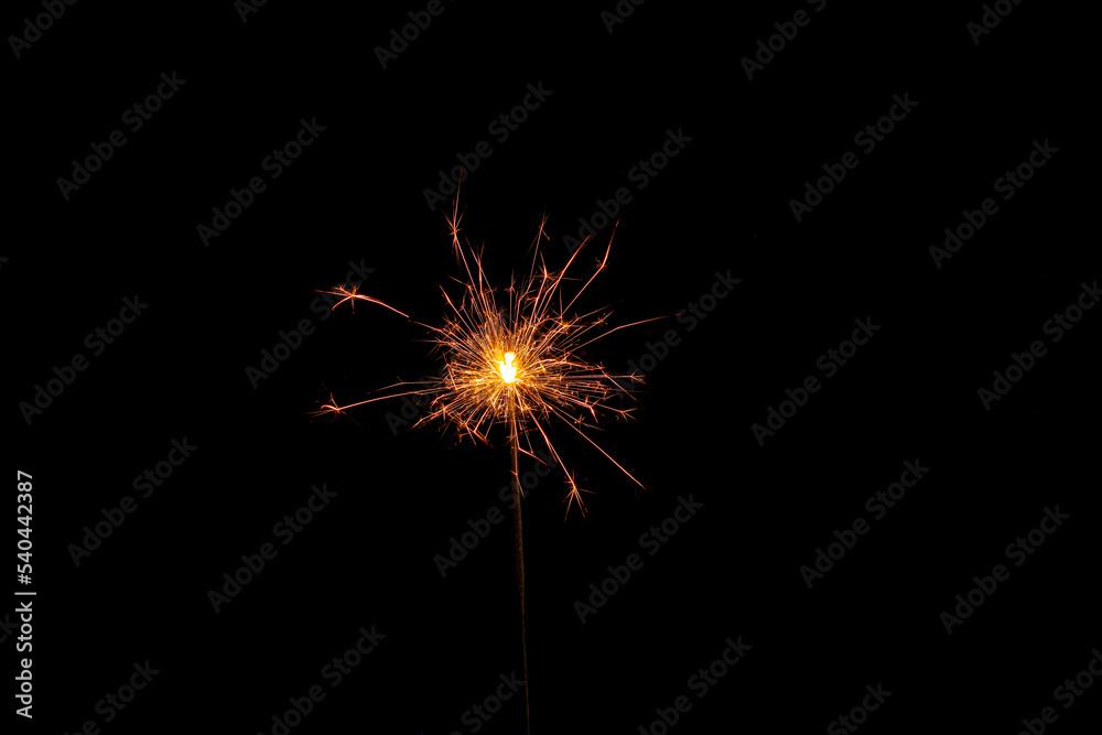 One burning sparkler stick on black background