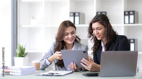 Two young Asian business woman talk, consult, discuss working with new startup project idea presentation analyze plan marketing and investment in the office.